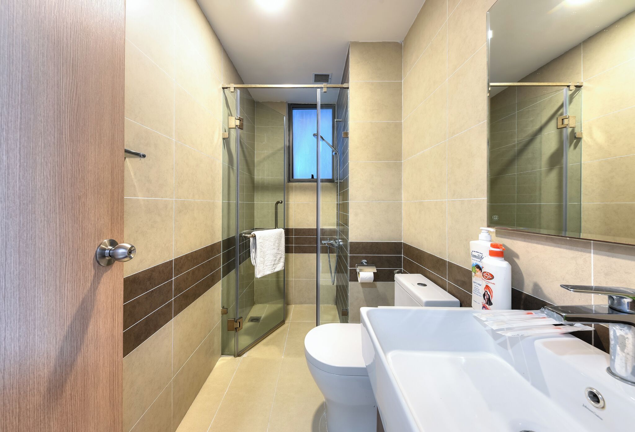 A modern bathroom with a glass shower enclosure, a toilet, and a sink.