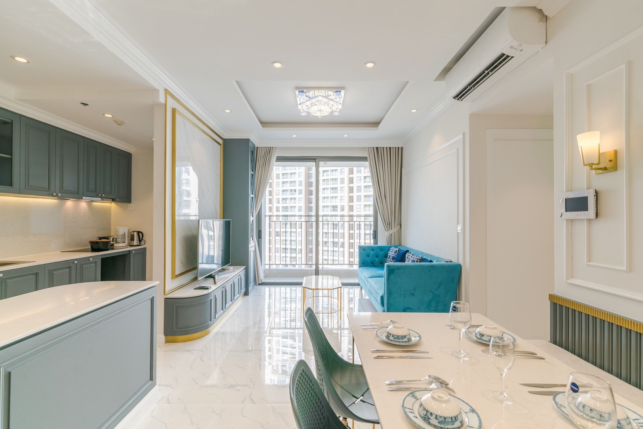 A modern kitchen with grey cabinets, a dining area with a white table set for four, and a large window with curtains.