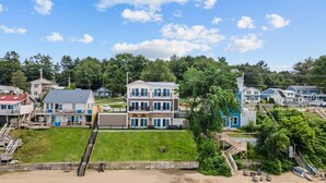 A coastal residential area with houses, a beach, and a water body. - Enjoy Sunsets at Fully Equipped 4BR-Lake Champlain (Colchester)