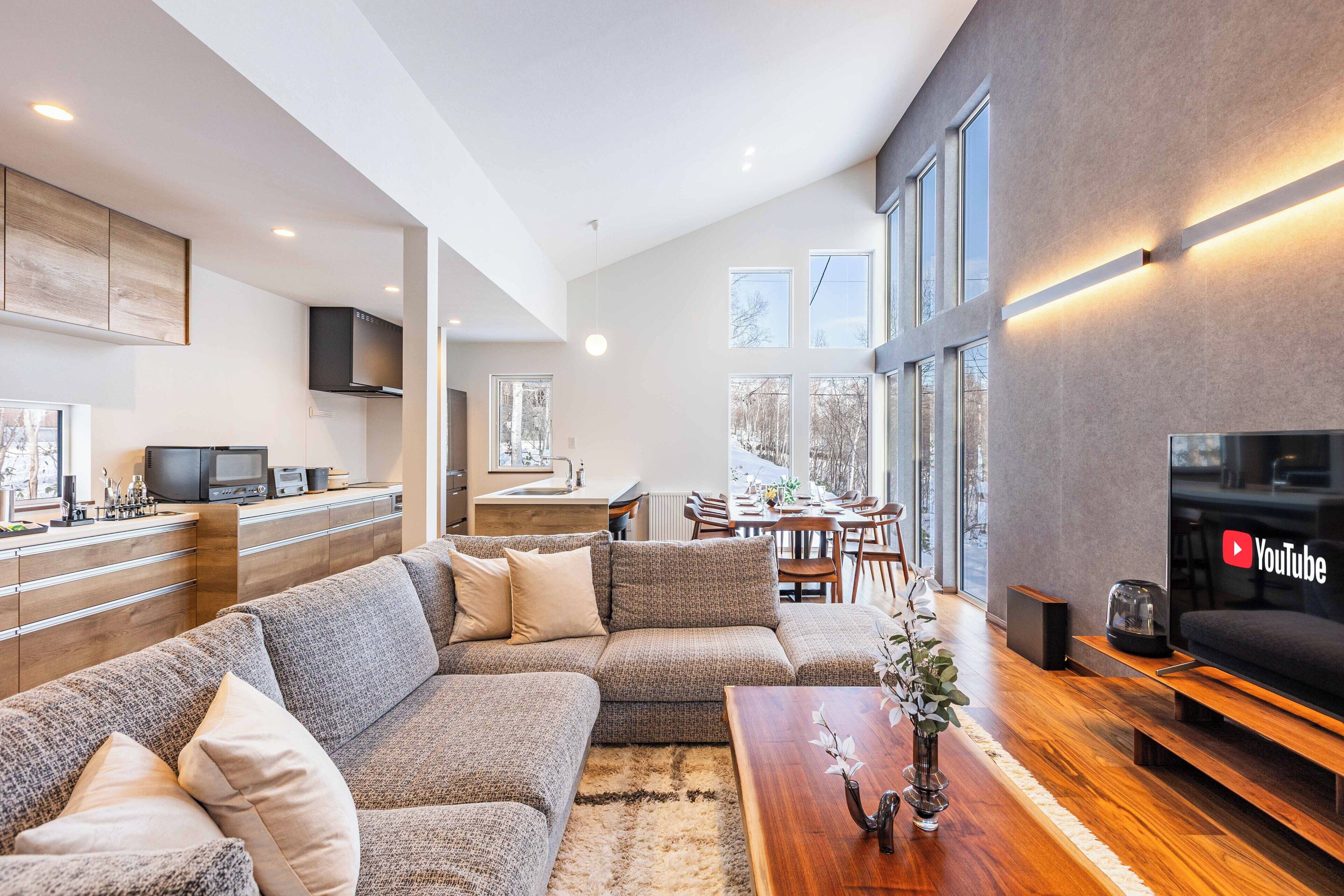 Un salon moderne avec un canapé d’angle, une table basse en bois et un téléviseur à écran plat.