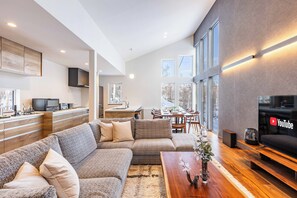 A modern living room with a sectional sofa, wooden coffee table, and a flat-screen TV.