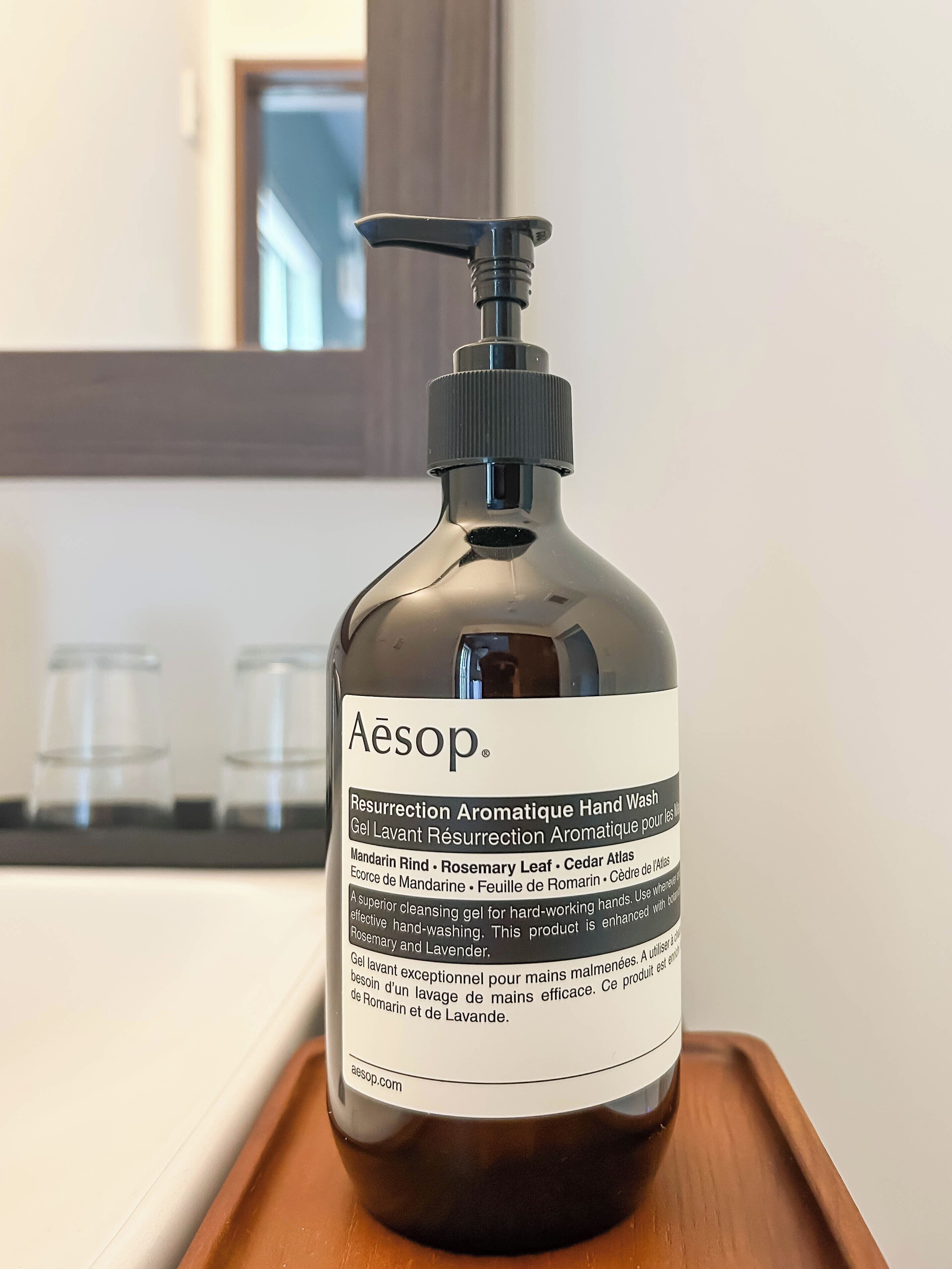 Eine Flasche Handseife mit dem Aufdruck 'Aesop' auf einem Holztablett.