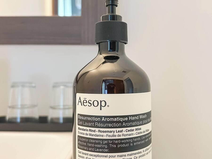 Eine Flasche Handseife mit dem Aufdruck 'Aesop' auf einem Holztablett.