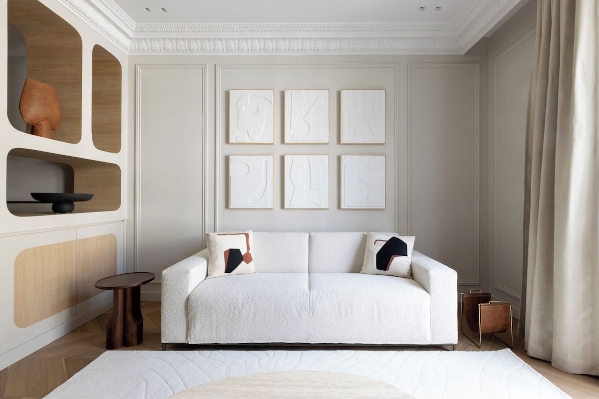 A modern living room with a sofa, decorative wall art, and a wooden cabinet.