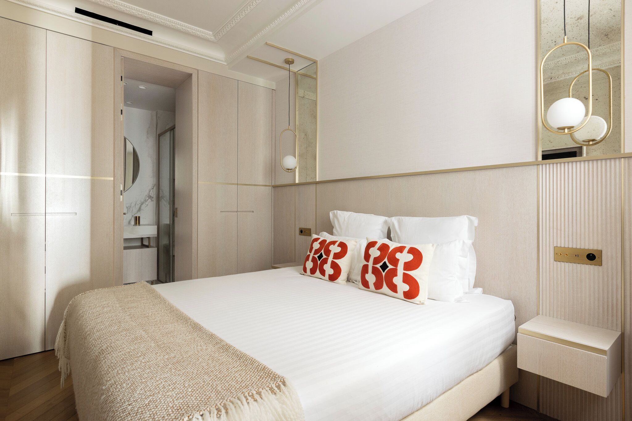 A modern bedroom with a large bed, a bedside table, a mirror, and a wardrobe.