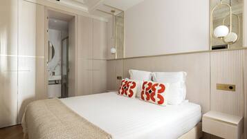 A modern bedroom with a large bed, a bedside table, a mirror, and a wardrobe.