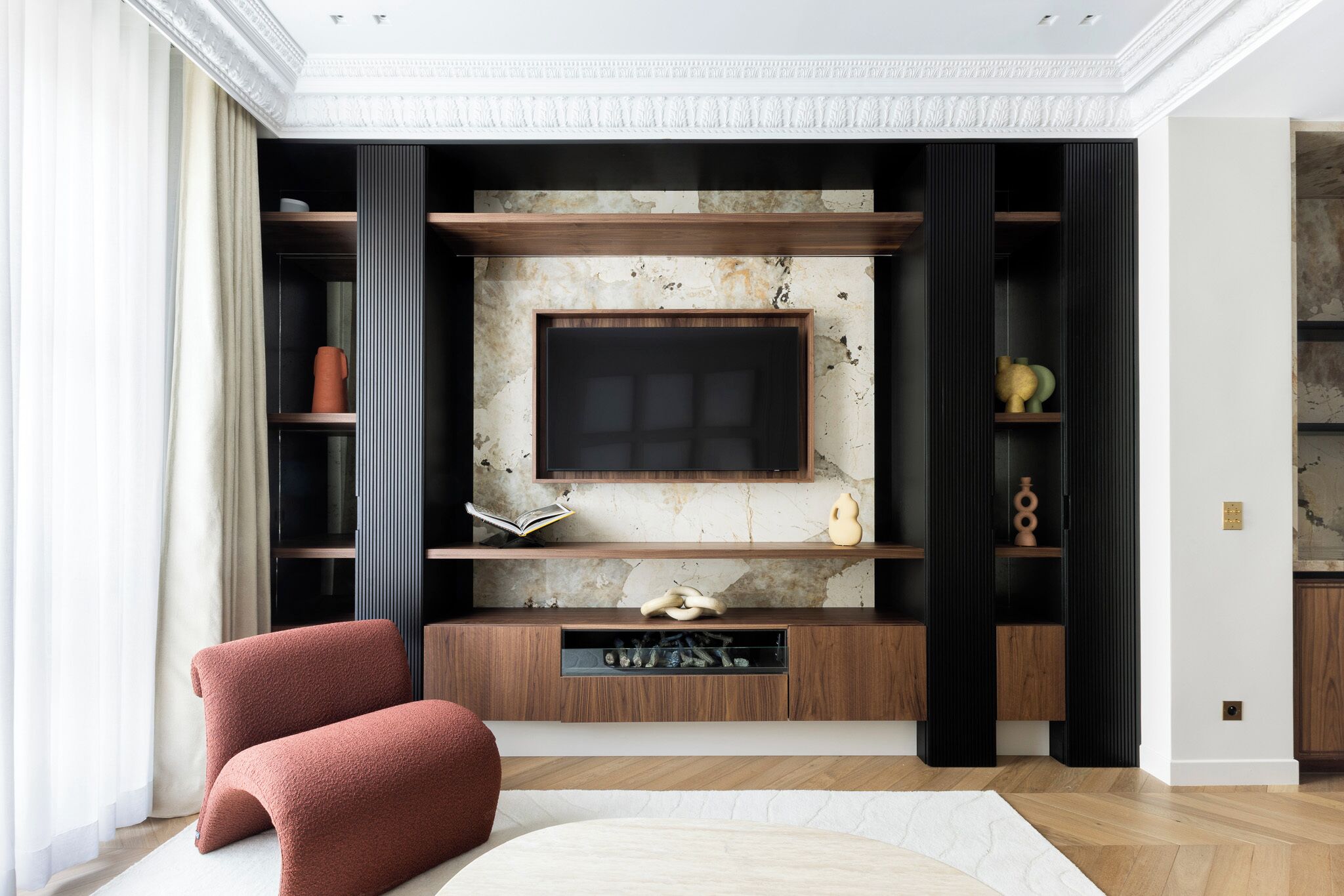 A modern living room with a fireplace, wooden shelves, and a large flat-screen TV.