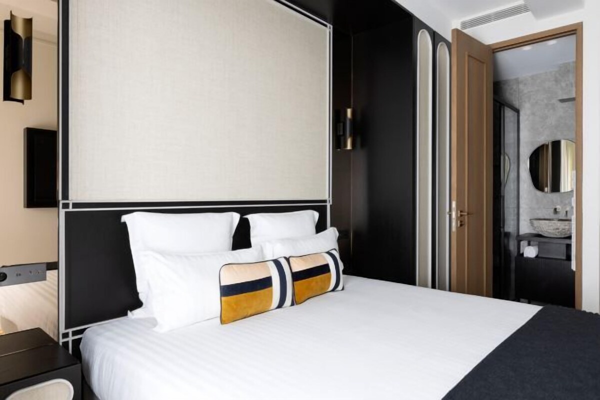 Una habitación de hotel moderna con una cama grande, una mesita de noche y un armario.