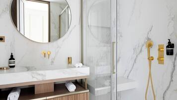 Ein modernes Badezimmer mit Marmorwaschtisch, Duschkabine aus Glas und goldenen Armaturen.