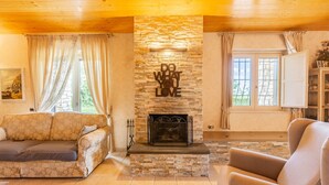 A cozy living room with a stone fireplace, a sofa, and a chair. - Villa Le Cicale - Irpinia (Prata di Principato Ultra)