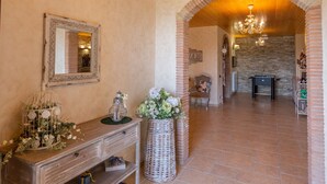 A hallway with a wooden bench, a mirror, a wicker basket with flowers, and a stone wall. - Villa Le Cicale - Irpinia (Prata di Principato Ultra)