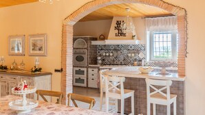 A kitchen with a brick archway, a chandelier, and a window with a view. - Villa Le Cicale - Irpinia (Prata di Principato Ultra)
