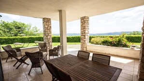 An outdoor patio with stone pillars, wicker furniture, and a view of a landscaped garden. - Villa Le Cicale - Irpinia (Prata di Principato Ultra)