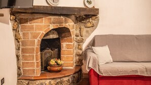 A stone fireplace with a flower vase, a red sofa, and a clock on the wall.