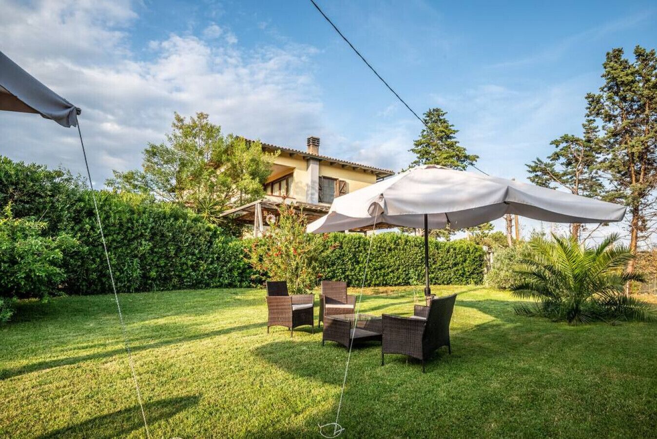 A well-maintained backyard with a patio area, outdoor furniture, and a large umbrella.