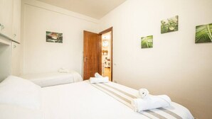 A hotel room with two beds, a wooden door, and three framed pictures on the wall. - Villa Santa Gabriella (Bagno di Gavorrano)