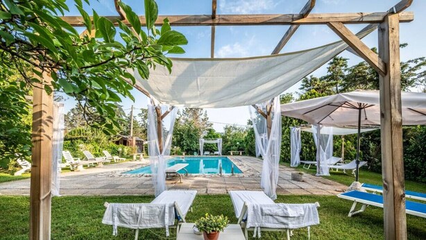 A covered outdoor area with a pool, lounge chairs, and a table with a potted plant. - Villa Santa Gabriella (Bagno di Gavorrano)