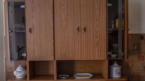 Ein Holzschrank mit mehreren Fächern, darunter Glastüren und ein unteres Fach mit einer weißen Schale.