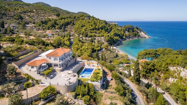 A large villa with a swimming pool, surrounded by lush greenery and a coastal view. - Penny Luxury Apartments (Samos)