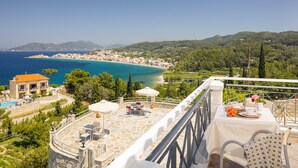 A terrace with outdoor seating, a pool, and a view of the coastline. - Penny Luxury Apartments (Samos)