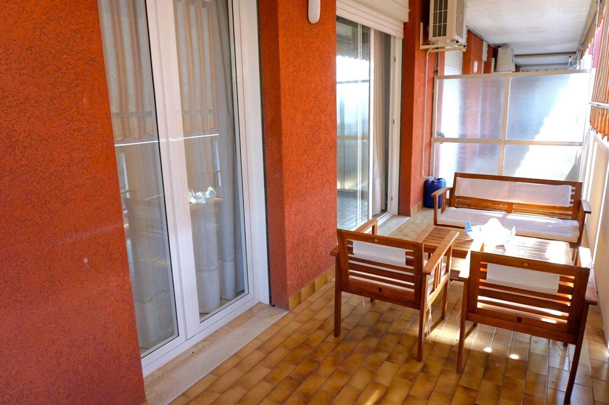 A balcony with a table and chairs, a sliding glass door, and a window.