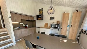 Een moderne keuken met een centraal eiland, houten kastjes en een magnetron.