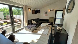 Een moderne woonkamer met een zwarte bank, een witte salontafel en een glazen deur naar een buitenruimte.
