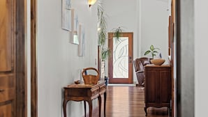 A hallway with a wooden floor, a wooden table with a basket, a chair, a cabinet, and a door with a glass panel. - Beautiful family home, spacious living and only minutes from the beach. (Coos Bay)