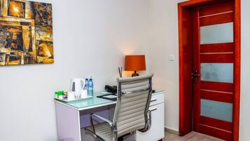 Un petit bureau comprenant un bureau, une chaise et une porte rouge.