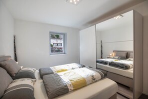 A bedroom with a bed, a window, a mirror, and a bedside table. - Apartment 'Obkircher' with Mountain View, Terrace, Garden and Wi-Fi (Nova Ponente)