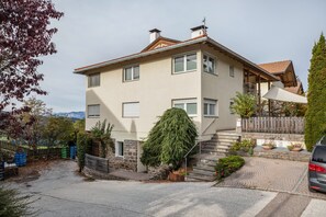 A two-story house with a stone facade, a wooden deck, and a staircase leading to the upper floor. - Apartment 'Obkircher' with Mountain View, Terrace, Garden and Wi-Fi (Nova Ponente)