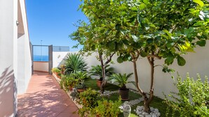 Un balcón con plantas en macetas, un pequeño árbol y una vista despejada del mar.