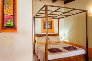 A four-poster bed with a wooden frame, a white bedspread, and two purple towels on the bed.