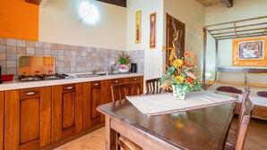 Una cocina con armarios de madera, estufa a gas, lavamanos y una mesa de comedor con sillas.