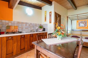 Una cucina con mobili in legno, un fornello a gas, un lavandino e un tavolo da pranzo con sedie.