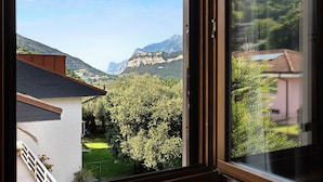 A view from a window overlooking a mountainous landscape with a building and a tree in the foreground. - Villa 'Katzemburg 5+' with Lake View, Private Garden and Wi-Fi (Arco)