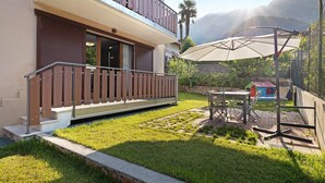 A modern building with a balcony, a patio with a table and chairs, and a view of mountains.