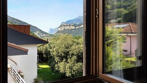 A view from a window overlooking a mountainous landscape with a building and a tree in the foreground.