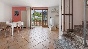 A spacious room with a dining table, chairs, a TV, and a staircase.