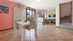 A spacious living area with a dining table, chairs, a sofa, and a staircase.
