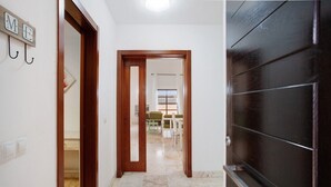 A hallway with a wooden door, a mirror, and a view into a dining area with a table and chairs.