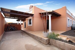 A building with a covered patio, a potted plant, and a bicycle.