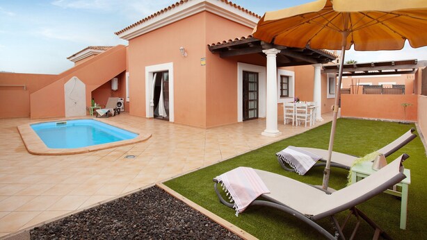 A pool, lounge chairs, a patio table, and a covered seating area.