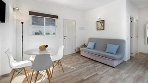 En moderne stue med sofa, spisebord, stole og fjernsyn.