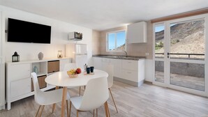A modern kitchen with white cabinets, a large window, and a dining area with a table and chairs.