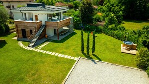 A modern two-story house with a patio, a hot tub, and a well-maintained lawn. - Apartment 'La Villa del Lago in Giardino' with Sea View, Wi-Fi and Air Conditioning (Colico Piano)