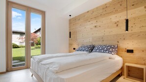 A bedroom with a large bed, wooden headboard, and a sliding glass door leading to a garden. - Apartment 'La Villa del Lago in Giardino' with Sea View, Wi-Fi and Air Conditioning (Colico Piano)