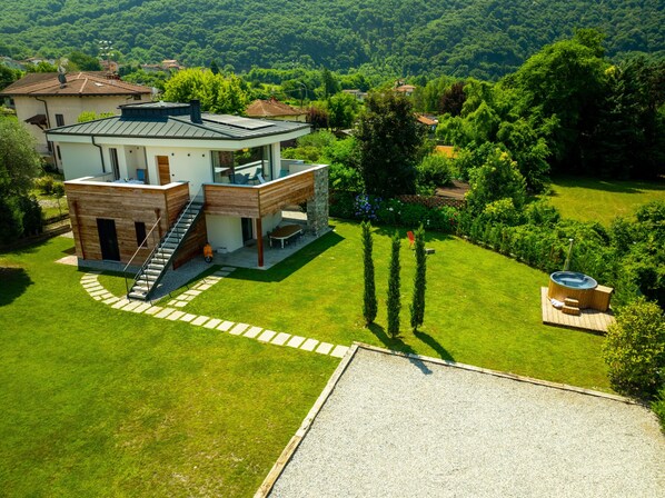 Une maison moderne à deux étages, dotée d’un patio, d’un jacuzzi et d’une pelouse bien entretenue.