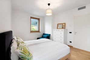 Une chambre à coucher avec un lit, une commode, une fenêtre et une porte.