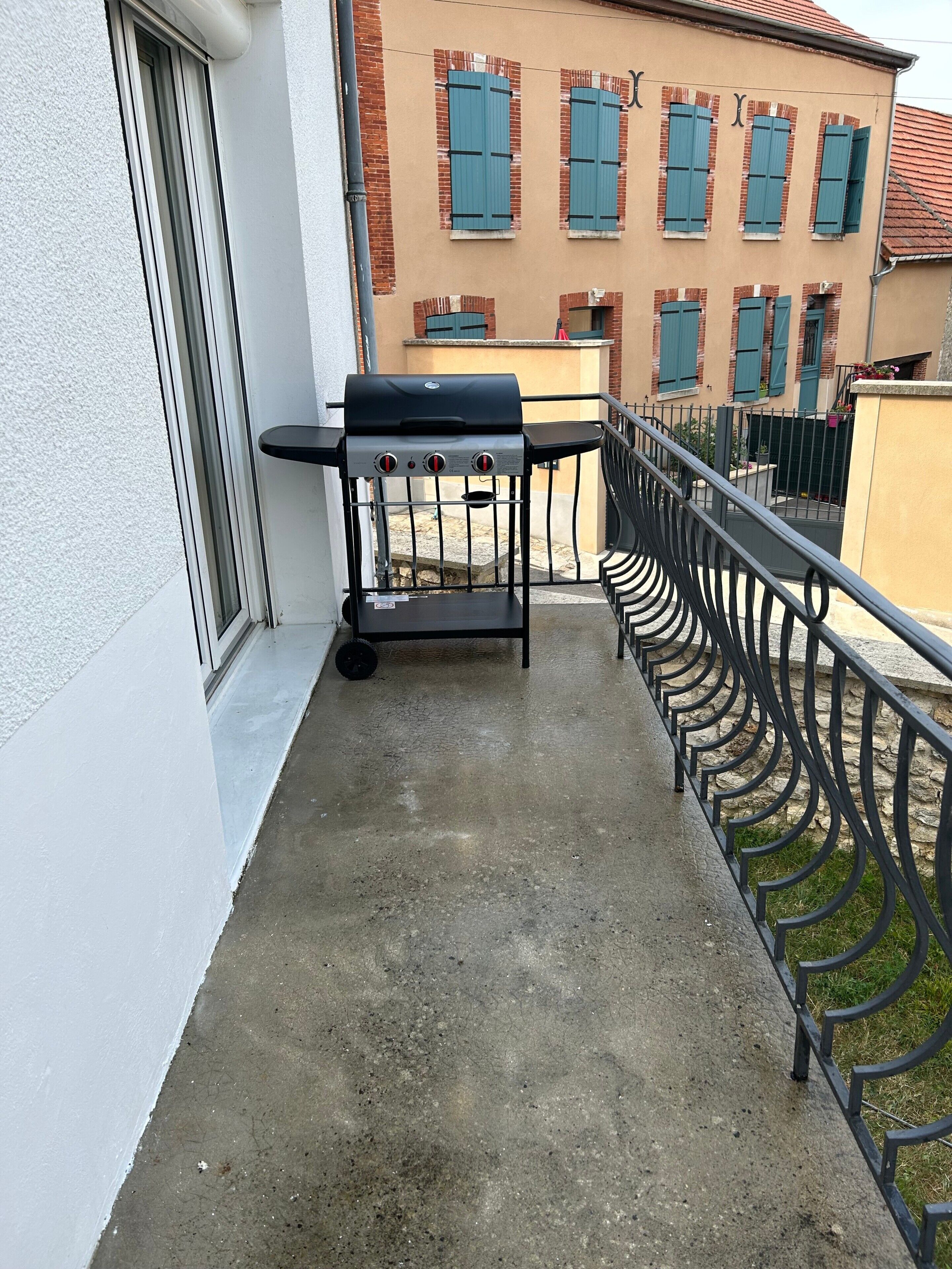 Ein Balkon mit Grill, Betonboden und Metallgeländer.